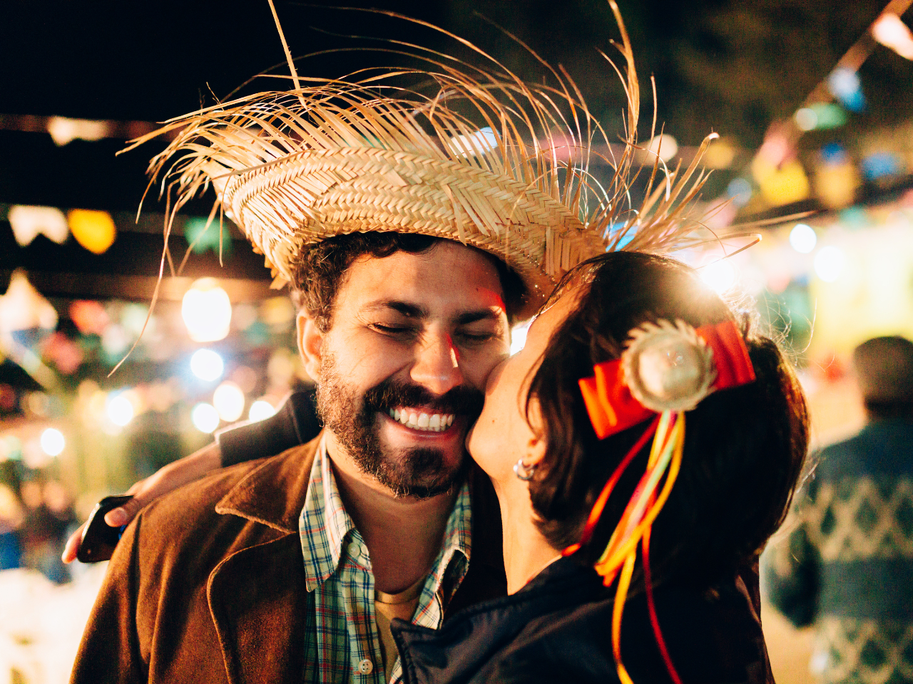 a woman kissing a man in the cheek at a festa junina